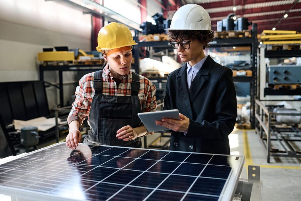 Confident manager with tablet showing young female engineer online data